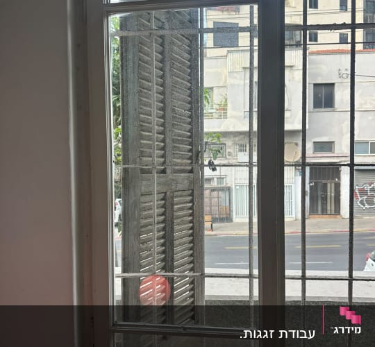 חלון זכוכית בדירה המציג זגוגיות חלון וסורגים במבט לרחוב